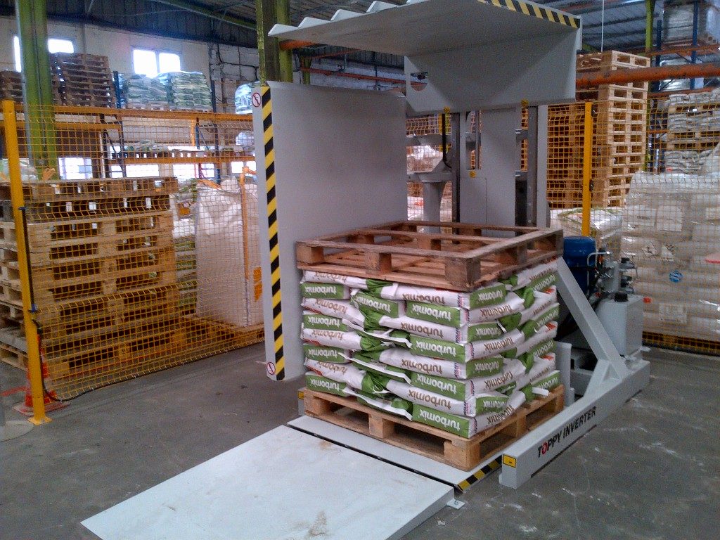 Stationary pallet inverter with manual or semi-automatic operation. Pallets are loaded into the machine from floor level